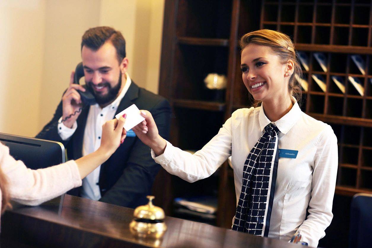 Hotel receptionist handing key card to guest